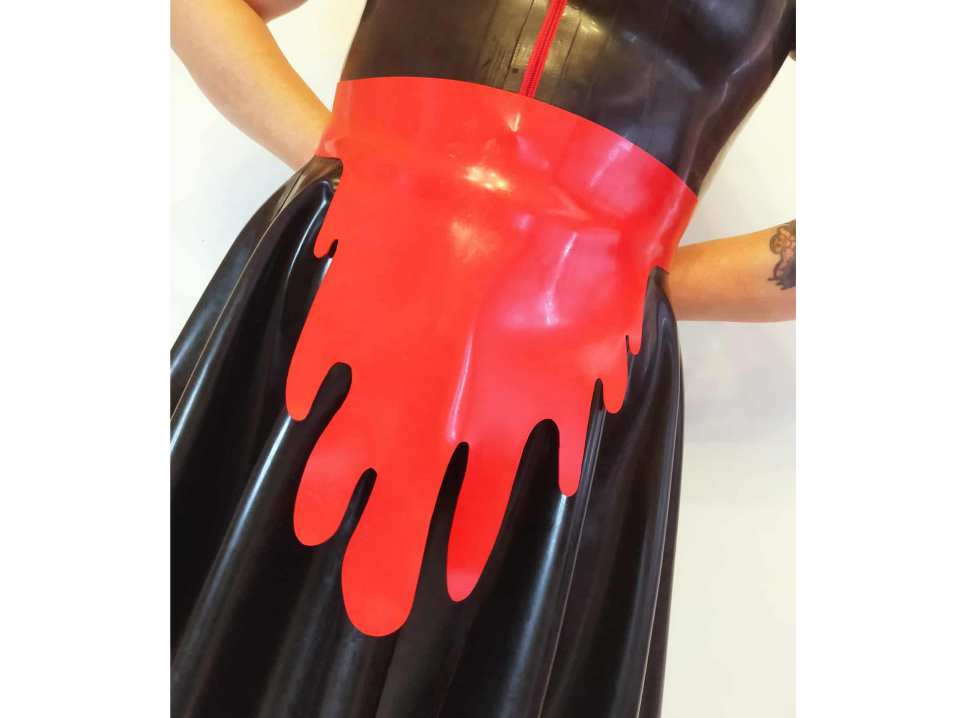 A vibrant red blood drip apron. Shown worn with a black latex swing dress the apron is 1mm thick with wavy drip hemline.
