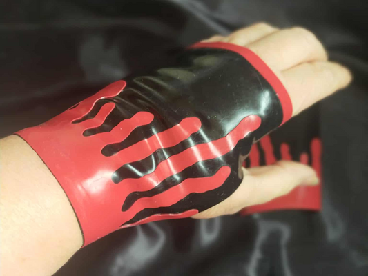Hand with black latex fingerless gloves with red blood drip appliques on a dark background