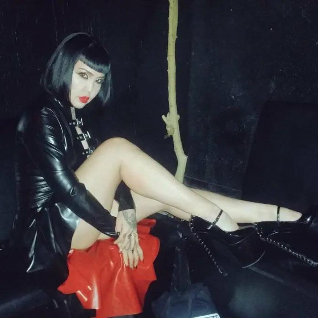 A black latex buckle coat with red latex inner lining. The coat has a waterfall effect from the hips.