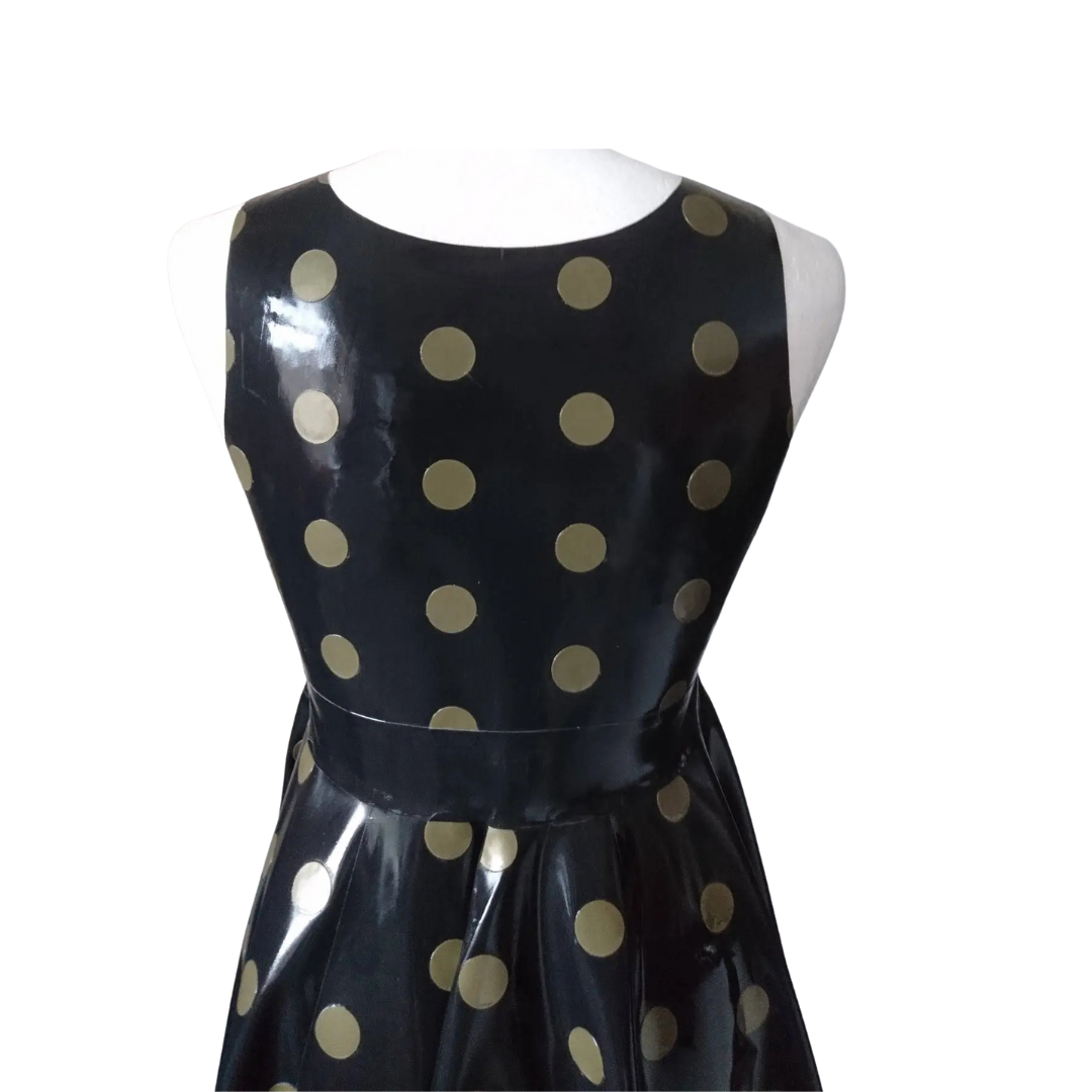 The back of a black sleeveless fit and flare dress with gold polka dots. It has a matching gold trim on the hemline.
