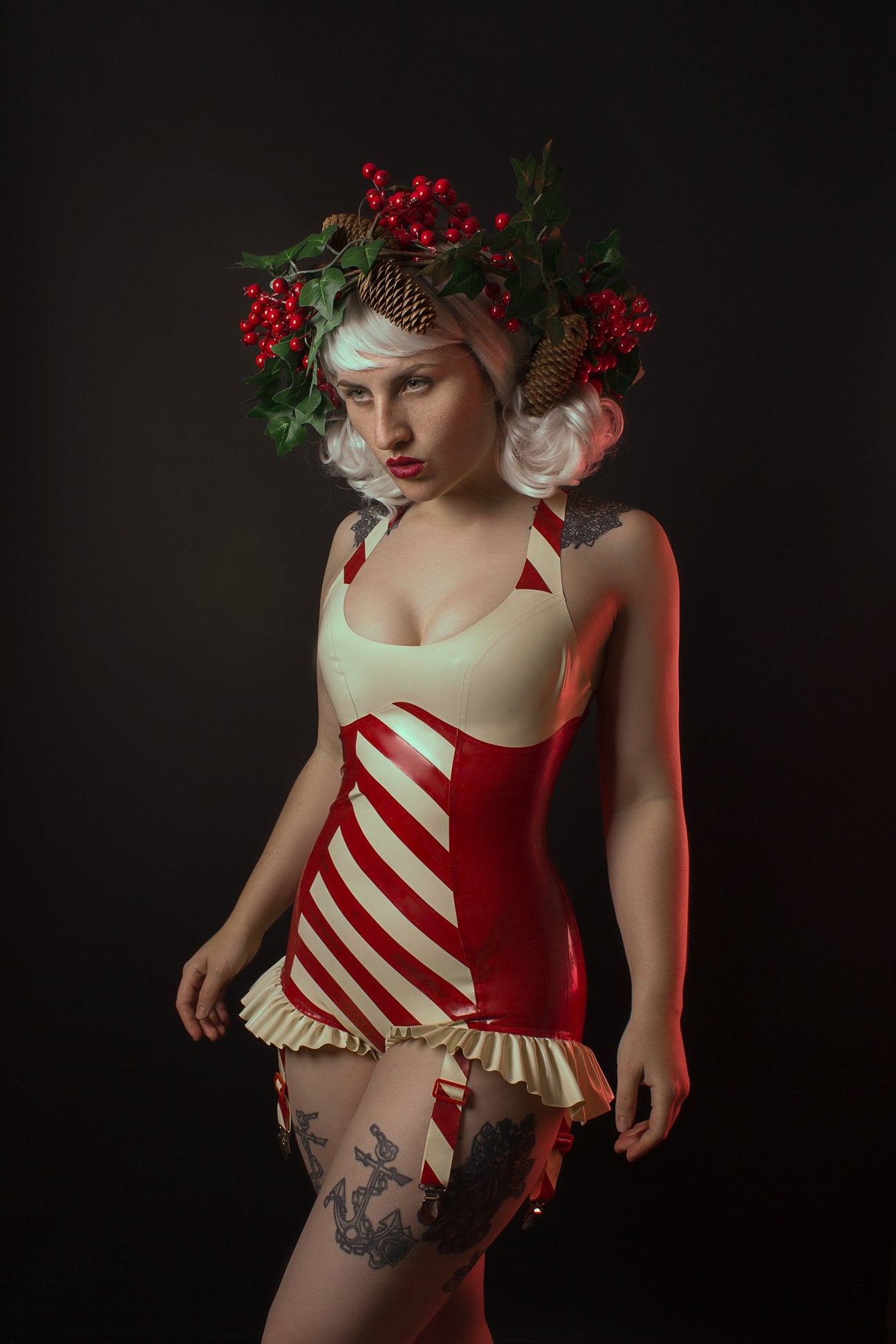 A fifties style red striped latex suspender bodysuit with white frilled detail. The front features red and white stripes.