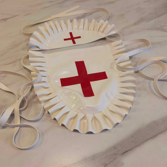 A white latex frilly nurse apron and cap with red cross detail.