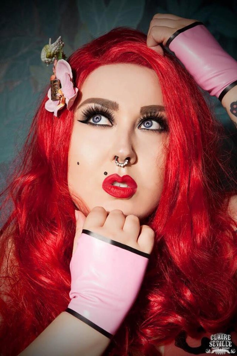 A pair of bubble gum pink latex fingerless gloves with black trim detailing.