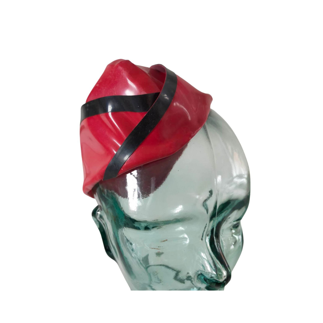 A red latex airline cap with black trim detail.