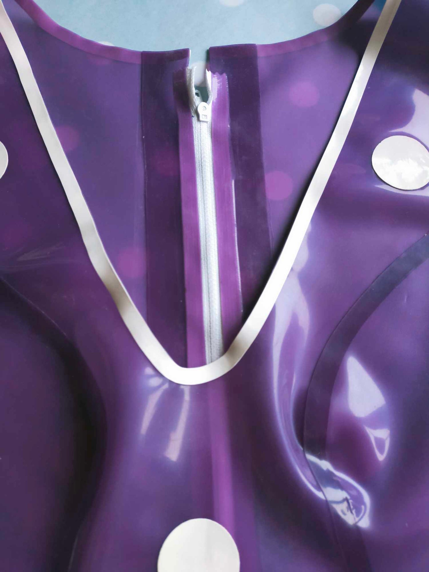 A purple latex playsuit with white trim and white polka dot appliques.