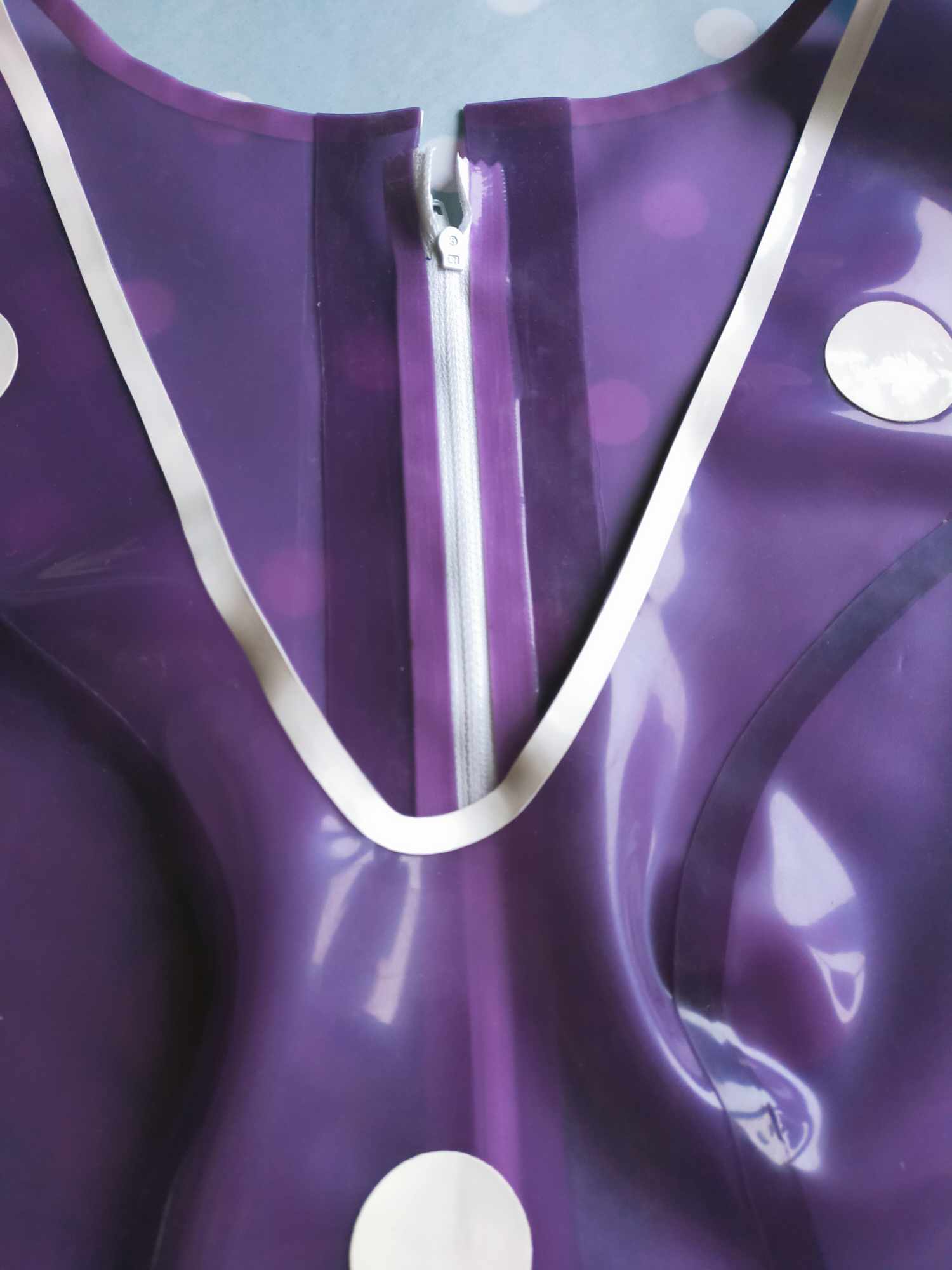 A purple latex playsuit with white trim and white polka dot appliques.