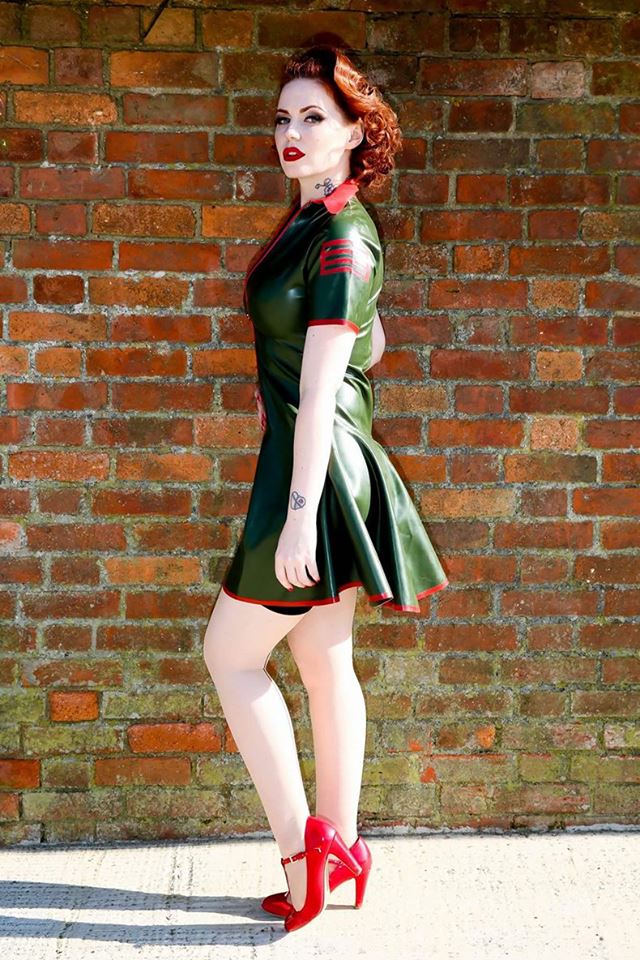 side of military latex swing dress with red trim.