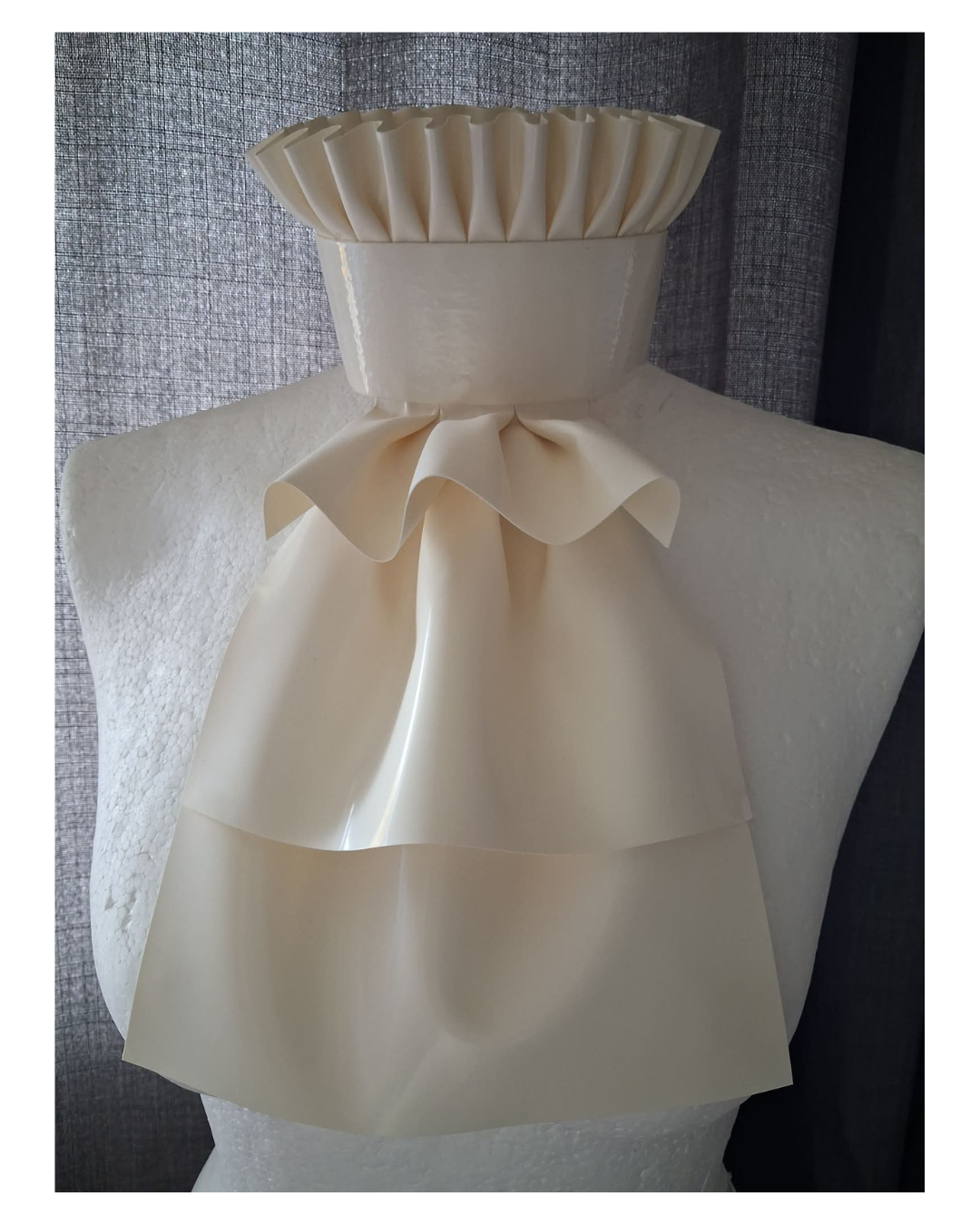 a white latex jabot with frill trim collar.
